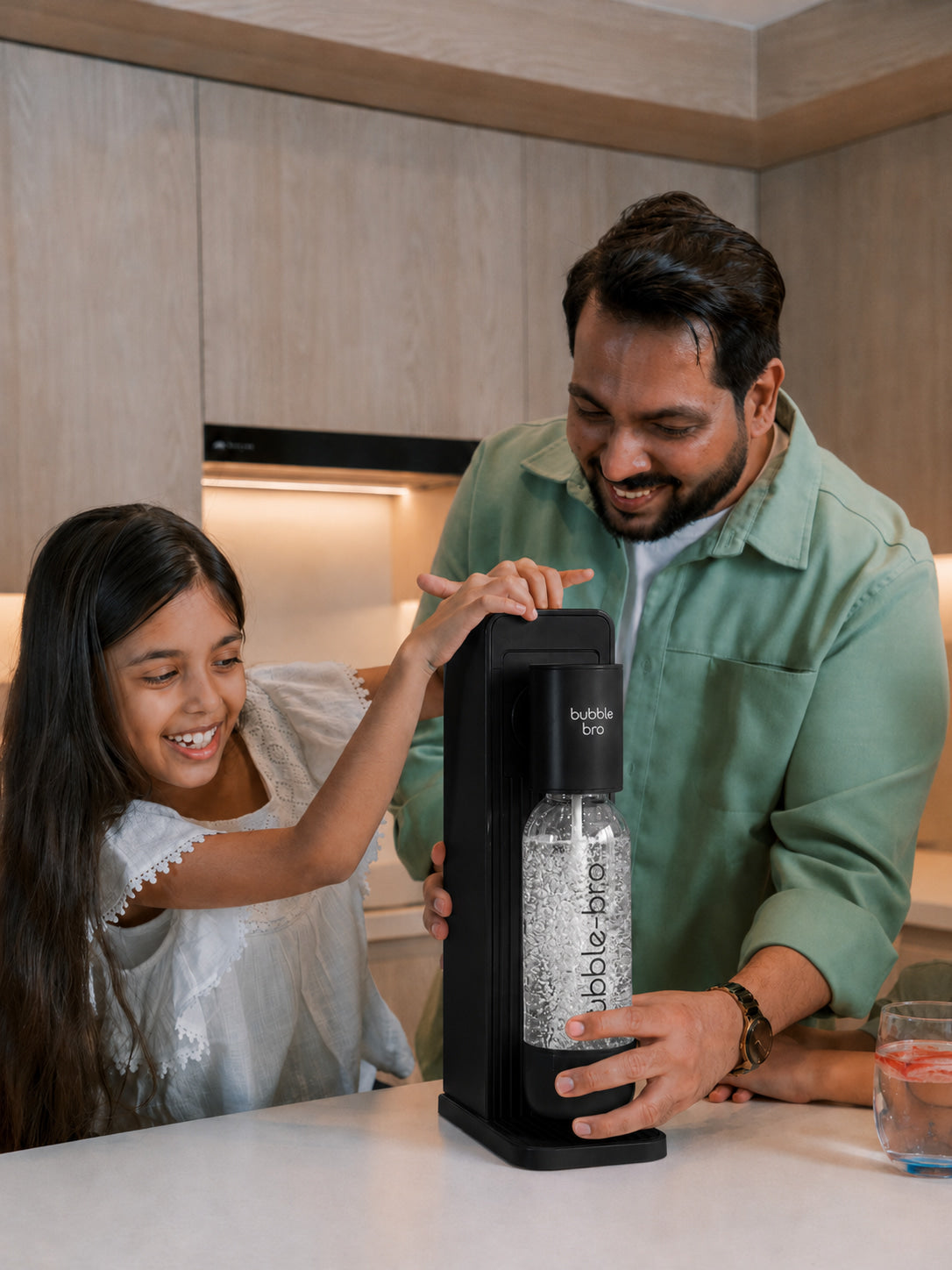 Father and daughter carbonating fresh sparkling water with the bubble-bro Origin in black at home in their modern kitchen