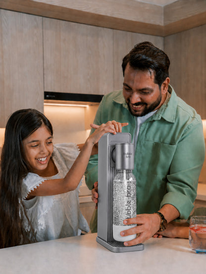 Father and daughter carbonating fresh sparkling water with the bubble-bro Origin in black at home in their modern kitchen 