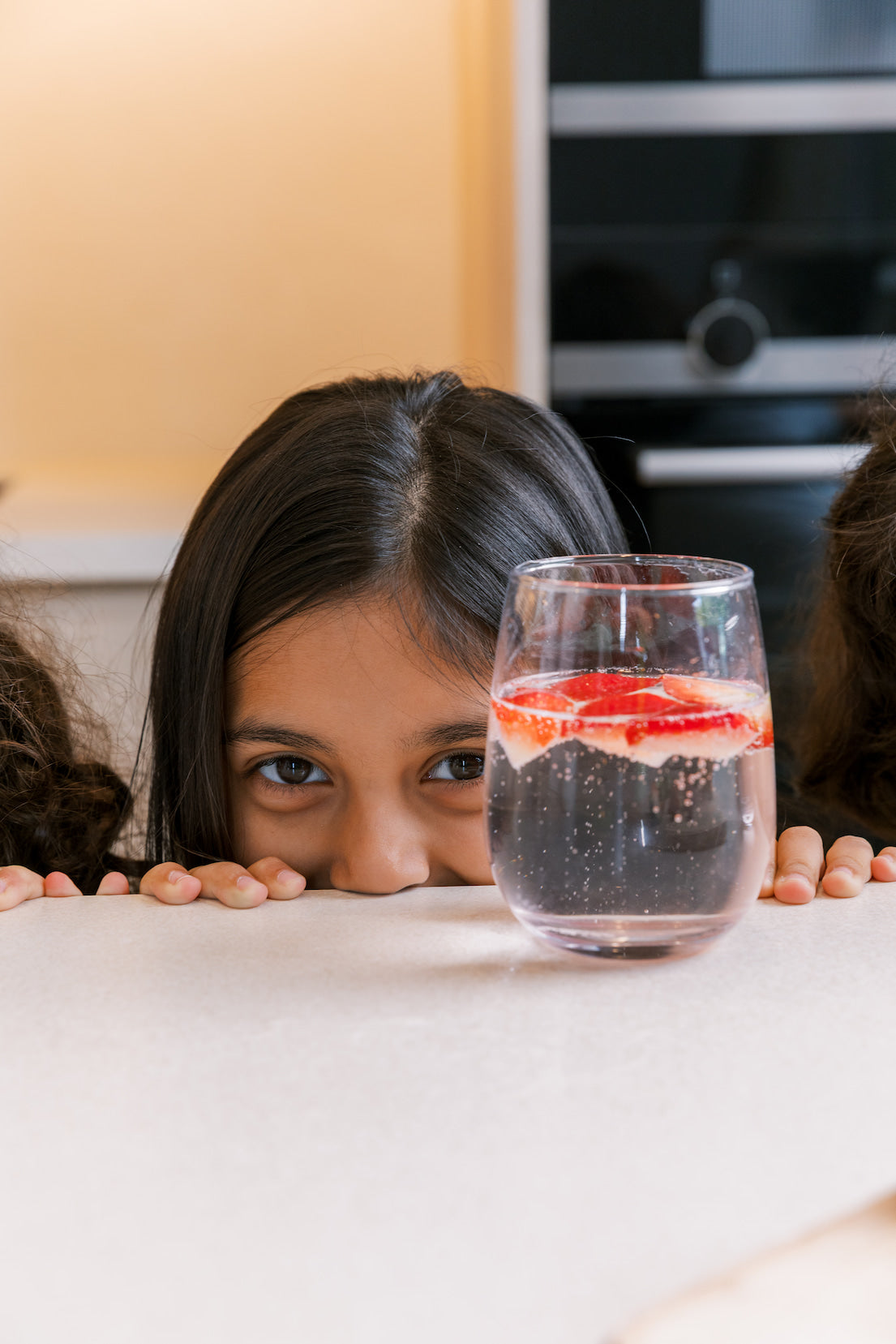 Young girl admiring a glass of fresh strawberry sparkling water made at home with the bubble-bro Origin — kid-friendly fizzy drink 