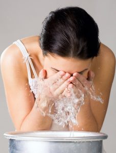 Image of isolated woman washing her face from wash-basin